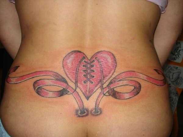A tatuagem no cóccix menina o coração e a fita