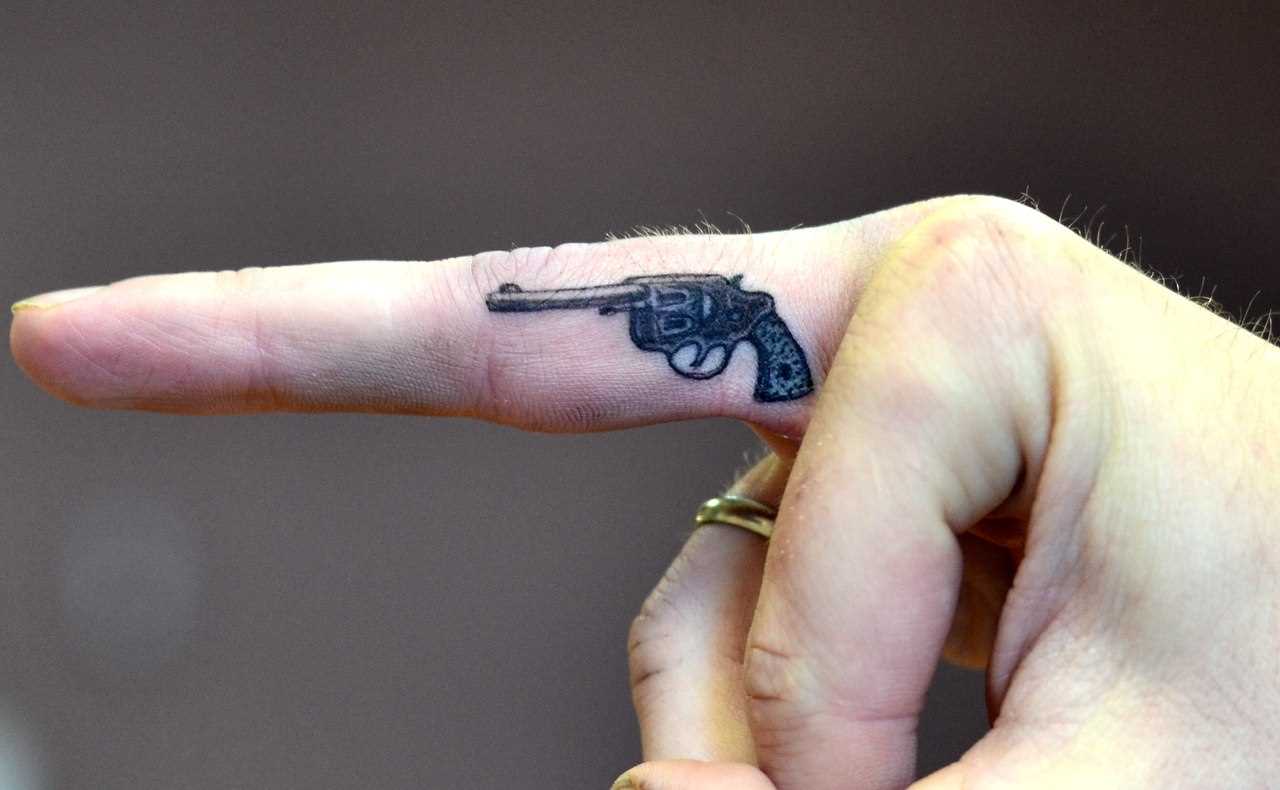 A tatuagem no dedo do cara - a arma