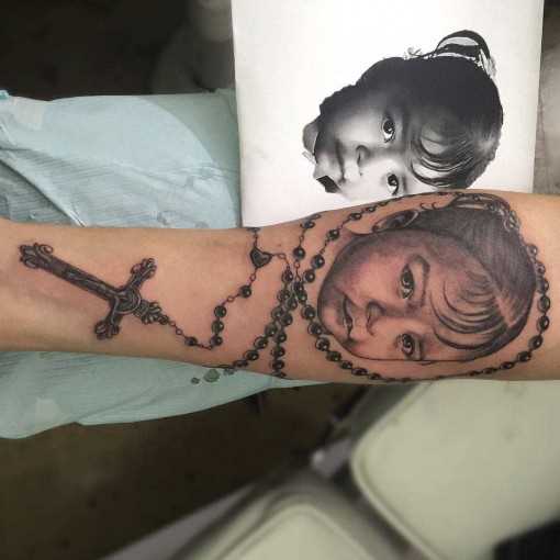 A tatuagem no estilo chicano no antebraço da menina - fotos de bebê com rosário