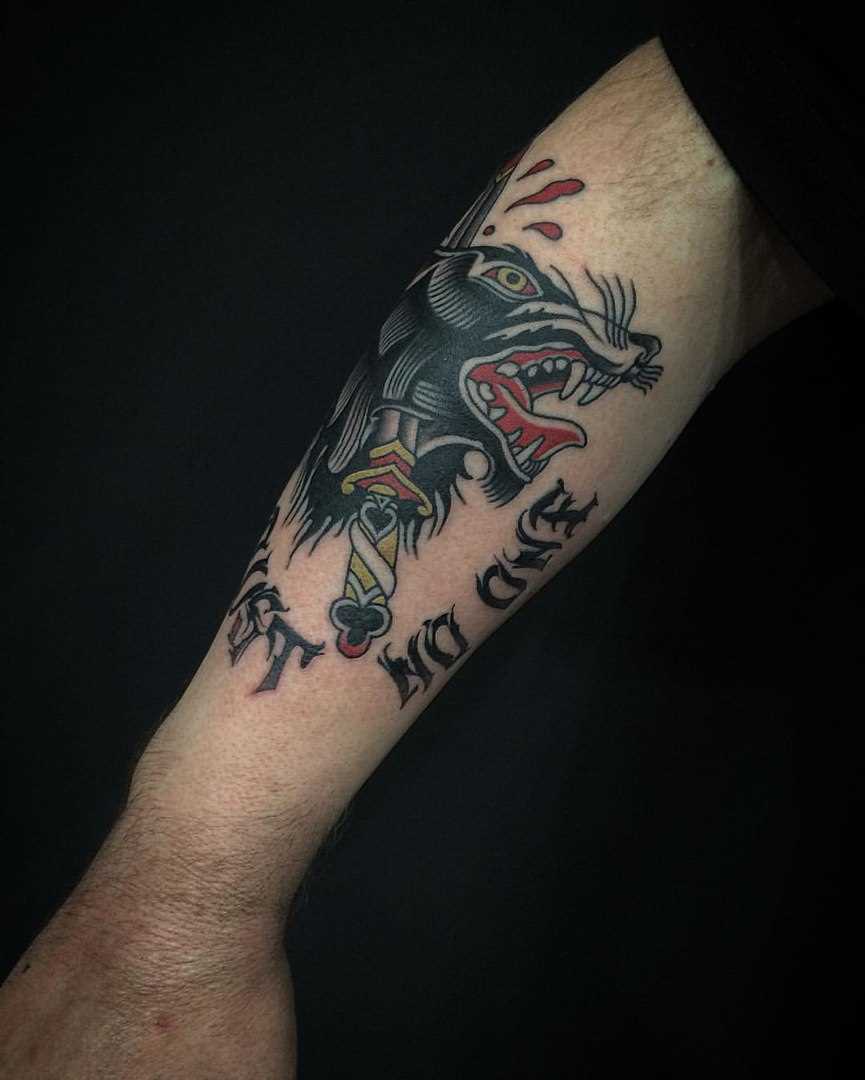A tatuagem no estilo oldschool na mão de um cara - a cabeça de um lobo kinzhale