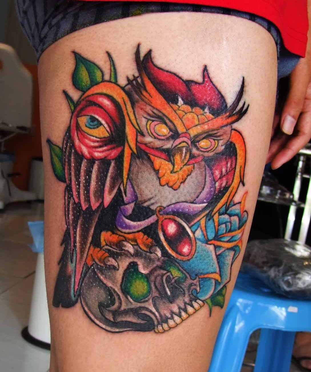 A tatuagem no estilo oldschool no quadril cara - de- coruja e o crânio