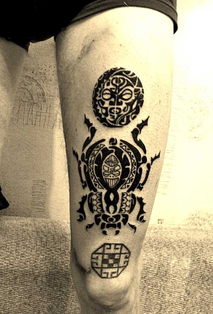 A tatuagem no estilo tribal na perna do cara - o besouro e a máscara de