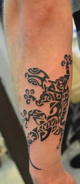 A tatuagem no estilo tribal no braço do homem - lagarto