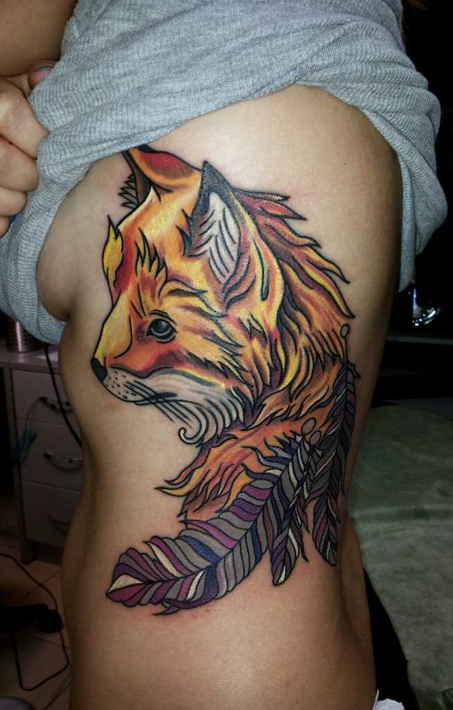 A tatuagem no lado da menina - a raposa e as penas