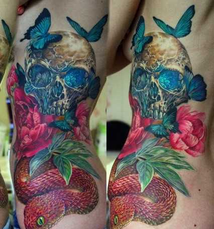 A tatuagem no lado da menina - cobra, crânio, rosa e borboleta
