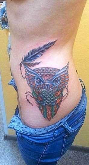 A tatuagem no lado da menina - coruja e penas