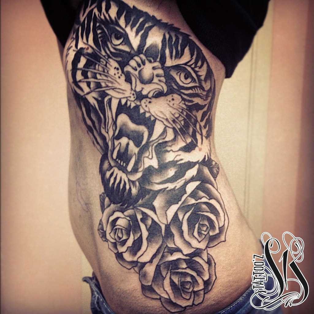 A tatuagem no lado da menina - o tigre e rosas