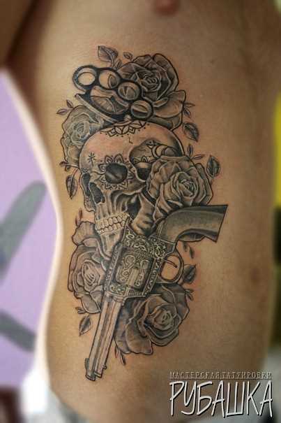 A tatuagem no lado do cara é a arma, o crânio e rosas