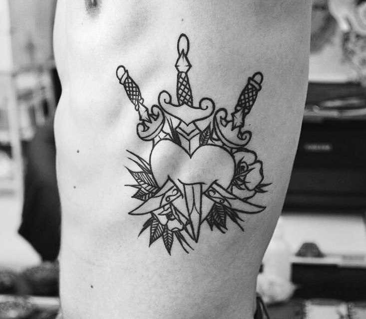 A tatuagem no lado do cara - o coração e os punhais