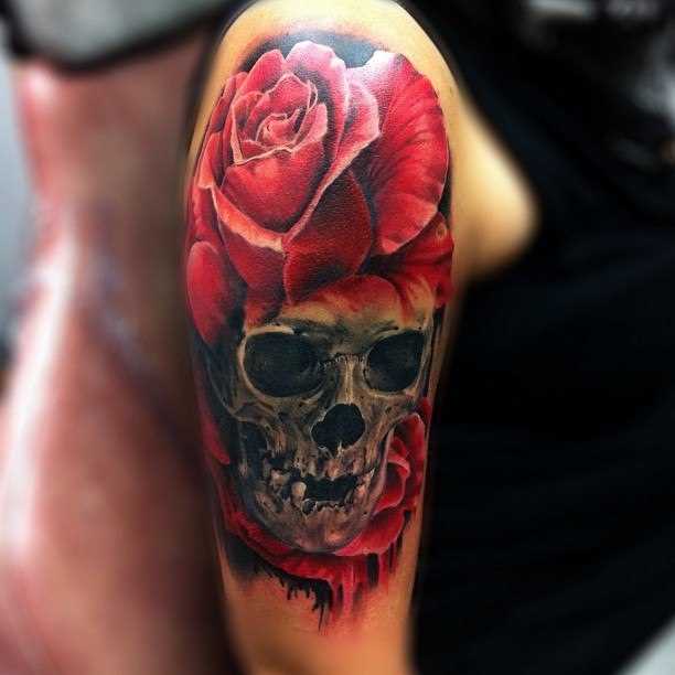 A tatuagem no ombro da menina de crânio e rosa