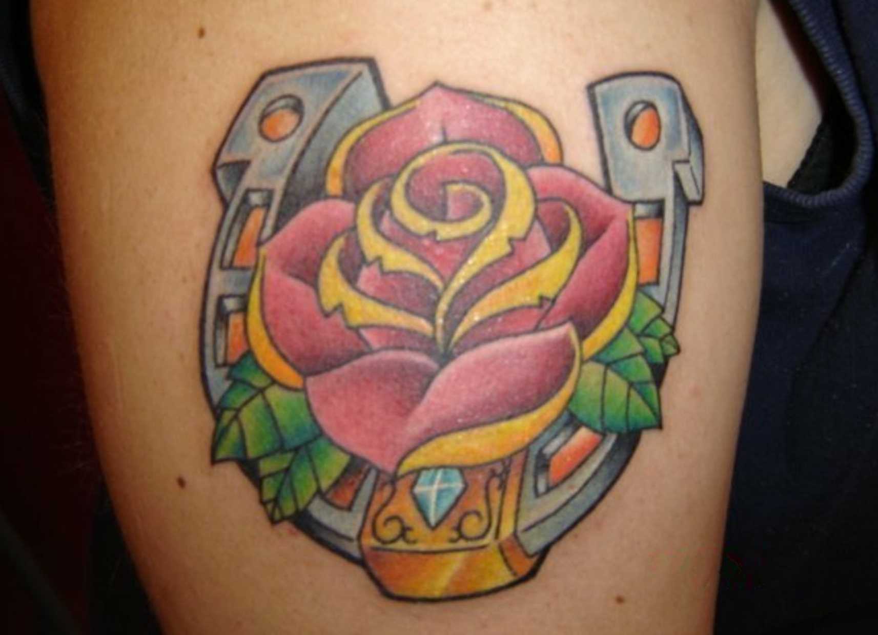 A tatuagem no ombro da menina - ferradura e rosa