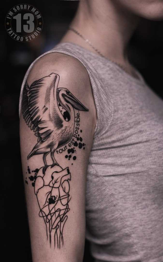 A tatuagem no ombro da menina - o coração e o pelicano