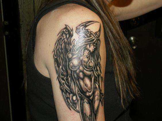 A tatuagem no ombro de um cara com a imagem de um diabo ou um anjo