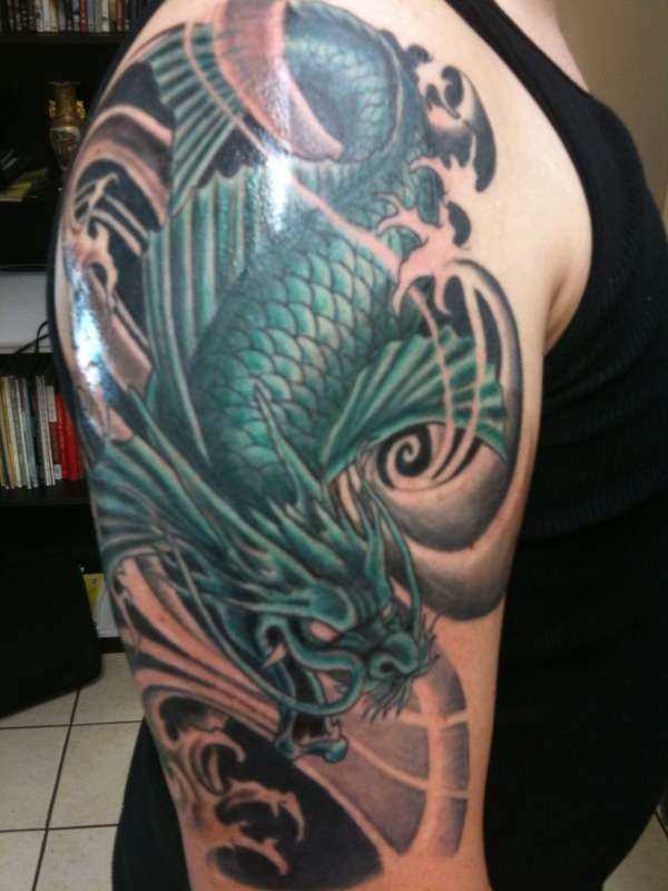 A tatuagem no ombro de um cara com a imagem de um dragão verde