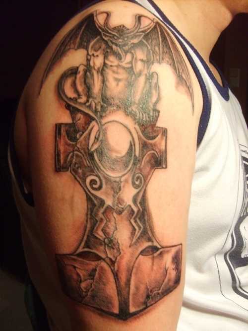 A tatuagem no ombro de um cara com a imagem de um martelo e o diabo