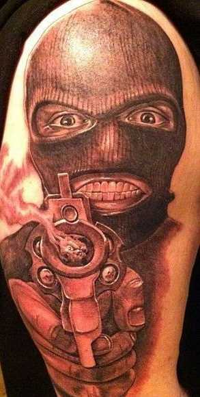 A tatuagem no ombro de um cara como o cara da máscara e com a arma
