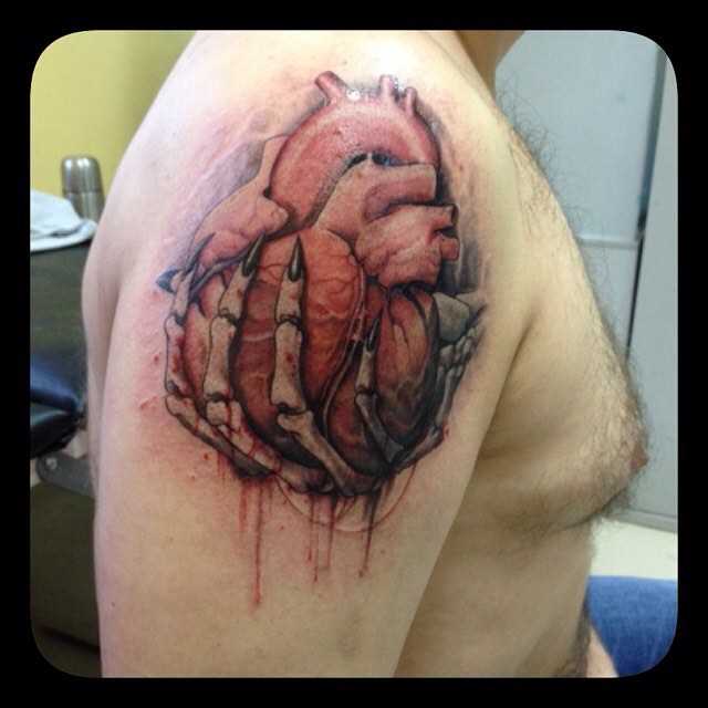 A tatuagem no ombro de um cara - coração na mão