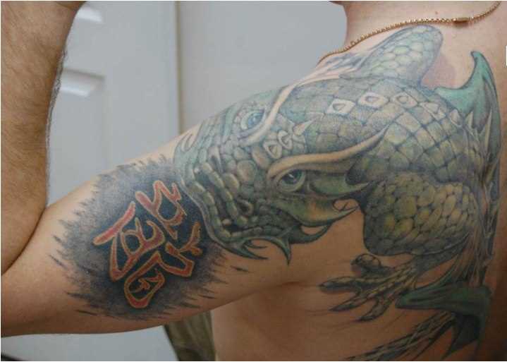 A tatuagem no ombro de um cara de dragão, e os hieróglifos
