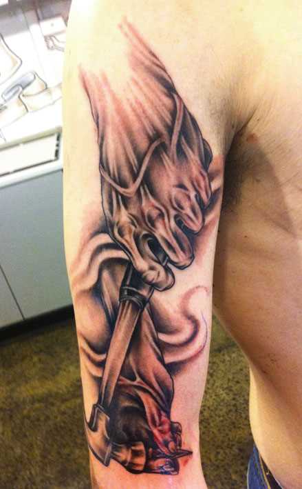 A tatuagem no ombro de um cara em forma de martelo na mão