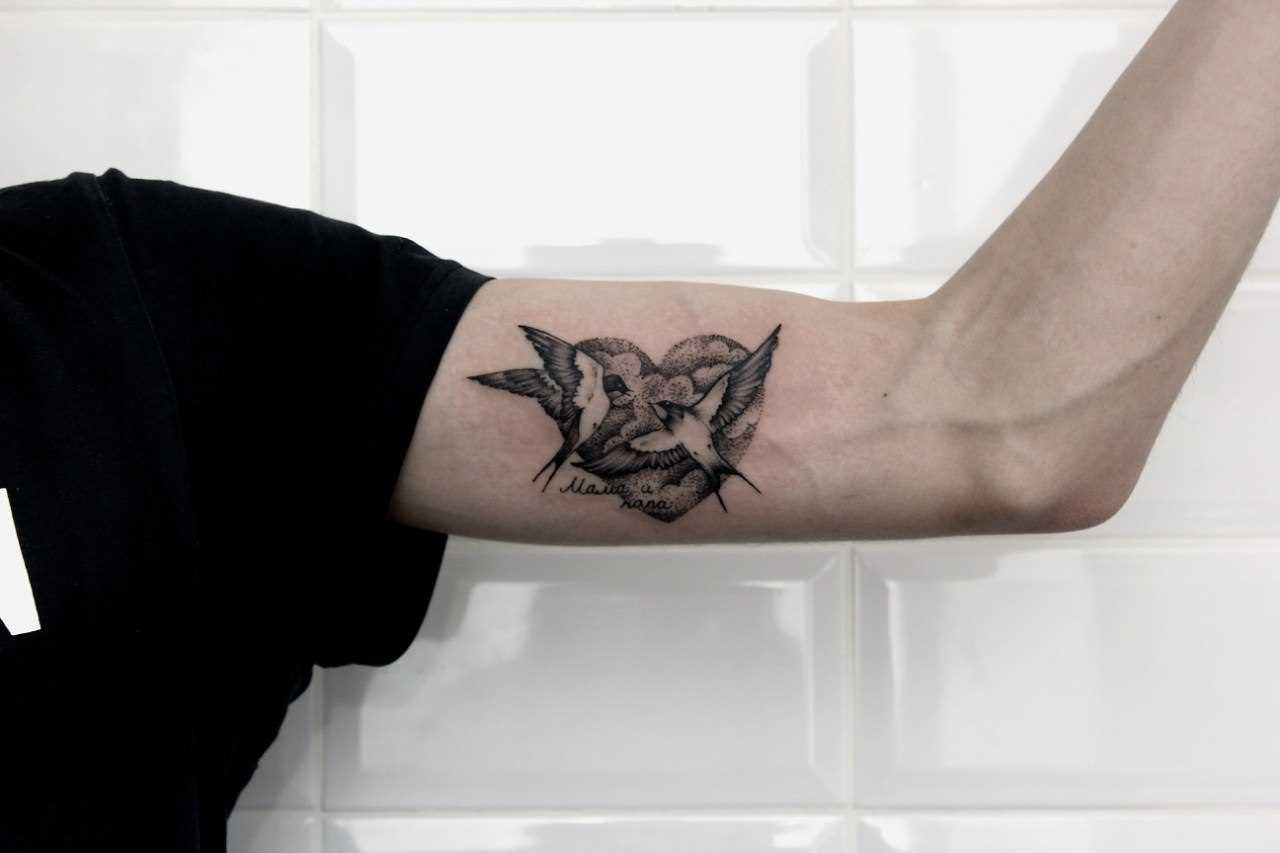 A tatuagem no ombro de um cara - o coração e as andorinhas