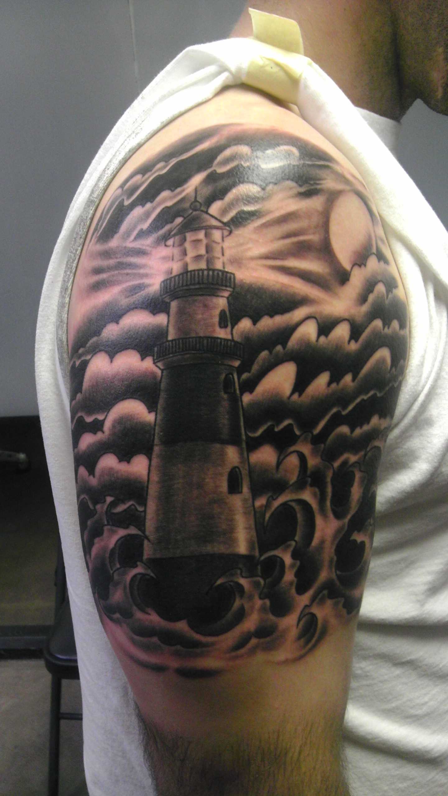 A tatuagem no ombro do cara - o farol e o mar