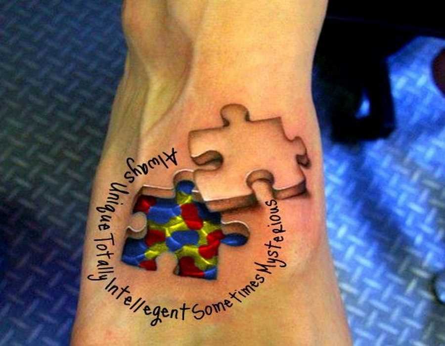 A tatuagem no pé de uma menina de quebra - cabeças e inscrição