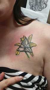 A tatuagem no peito da menina - o lírio e triângulo