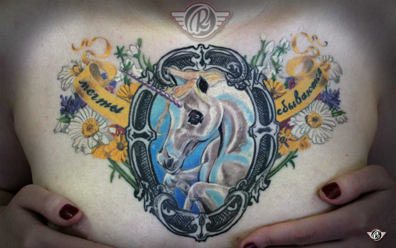 A tatuagem no peito da menina - um unicórnio e flores
