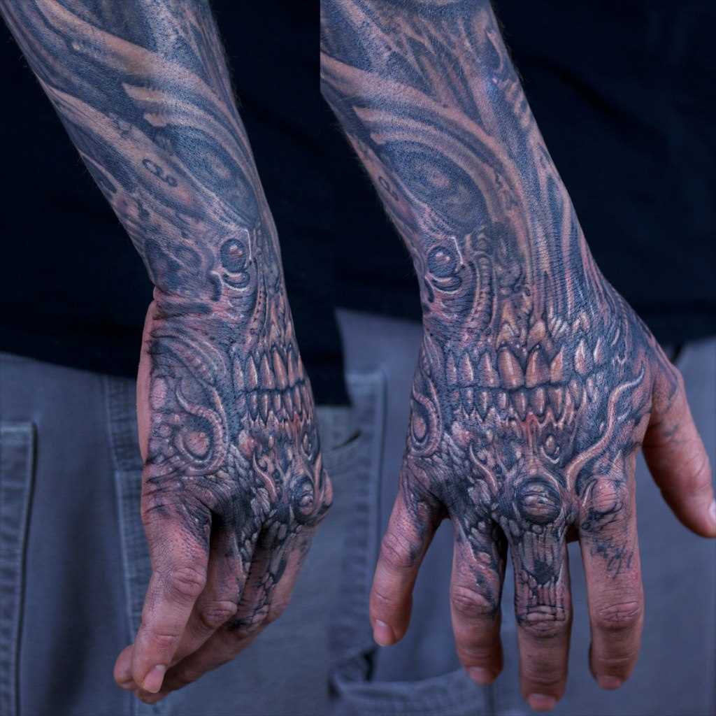 A tatuagem no pincel cara no estilo de biomecânica - estrangeiro