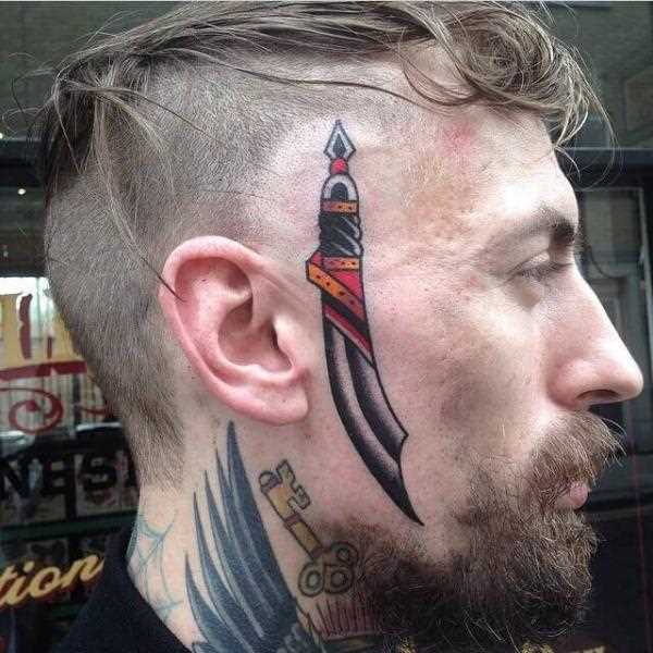 A tatuagem no rosto de um cara - um punhal no estilo oldschool