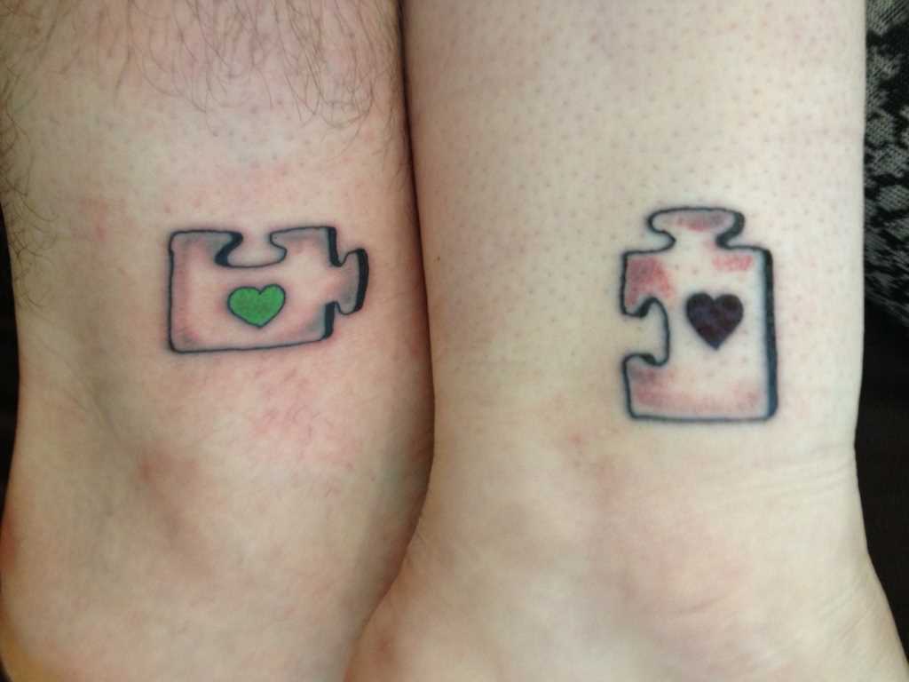 A tatuagem no shchikolotkakh menino e uma menina - quebra-cabeças com corações