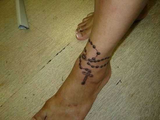 A tatuagem no tornozelo preto, as meninas cadeia e a cruz