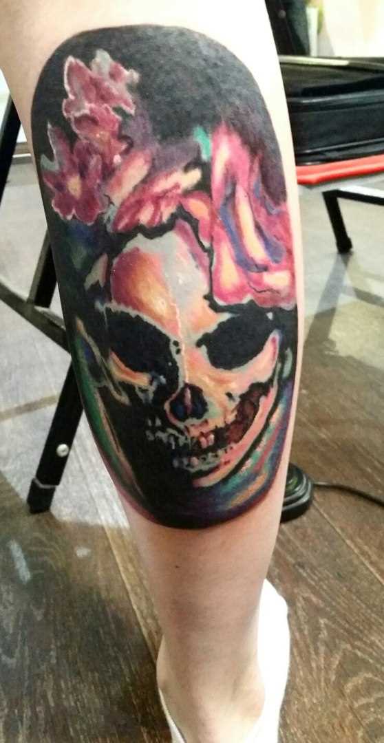A tatuagem sobre a perna de uma menina de crânio