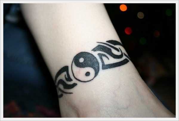 A tatuagem Yin e Yang no pulso da menina no estilo tribal