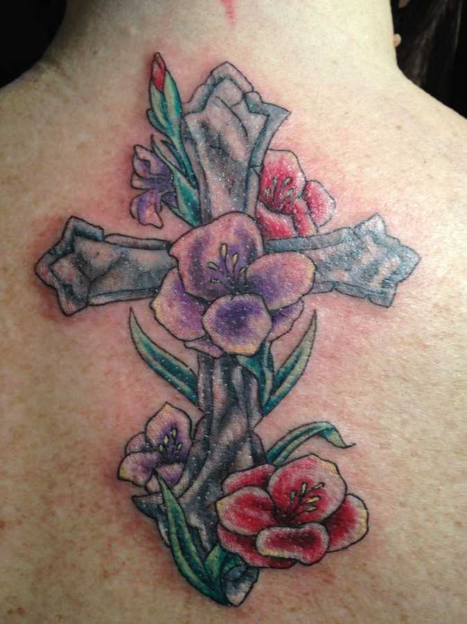 Bela tatuagem na coluna da menina - cruz e flores