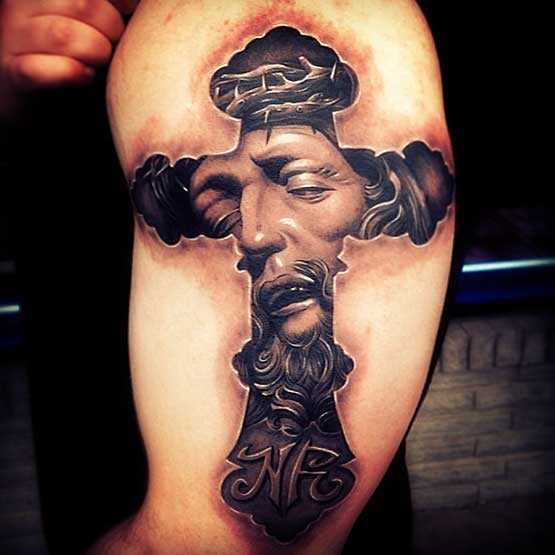 Bela tatuagem no ombro de um cara - a cruz e o rosto de Jesus
