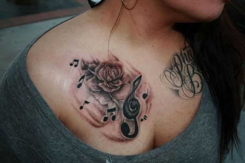 Bela tatuagem no peito da menina - as notas da clave de sol e rosa