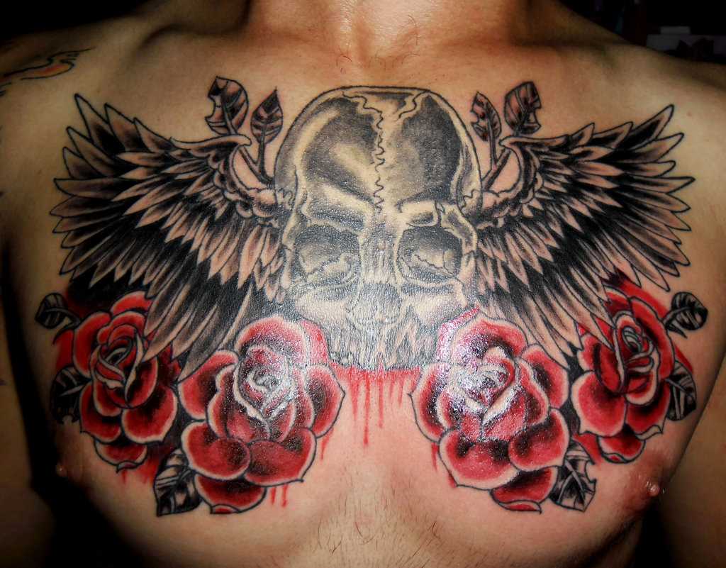 Bela tatuagem no peito de um cara - de- asas, a rosa e o crânio
