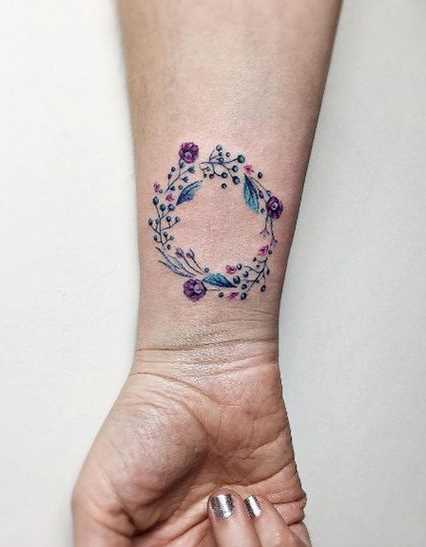 Cores de tatuagem de coroa de louro no pulso da menina
