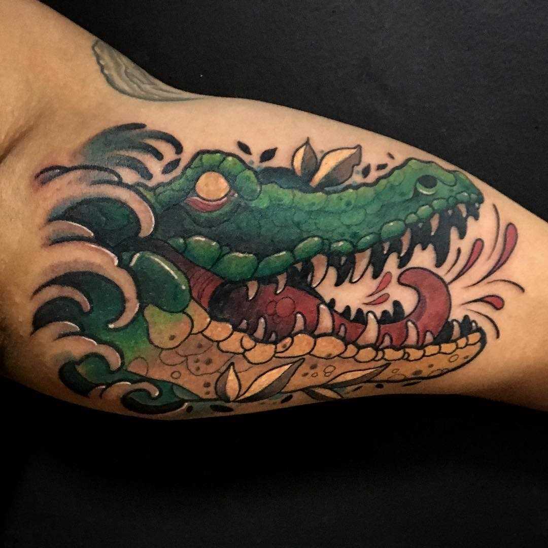 Cores de tatuagem de um crocodilo na mão de um cara