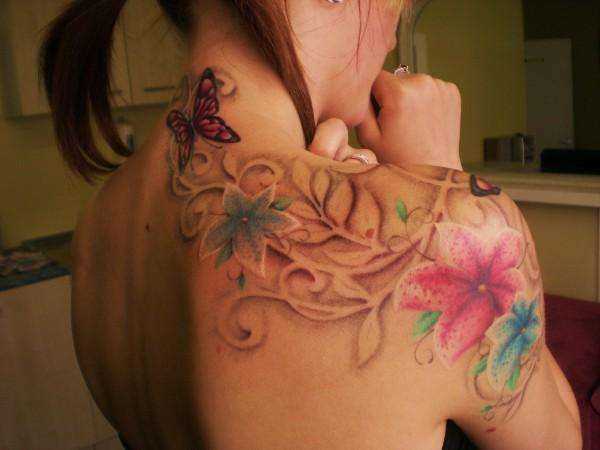 Cores de tatuagem no ombro da menina - o lírio e a borboleta