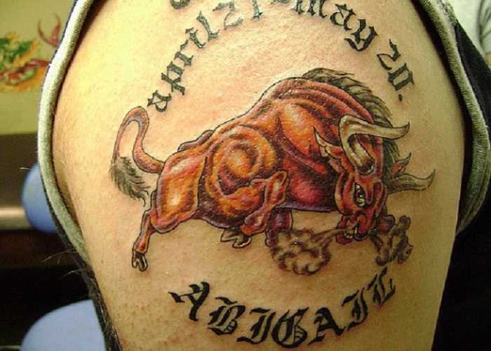 Cores de tatuagem no ombro de um cara em forma de um touro e inscrições