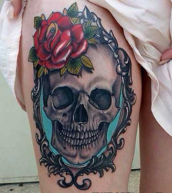 Foto a cores de tatuagem de caveira com uma rosa em estilo gótico no quadril da menina