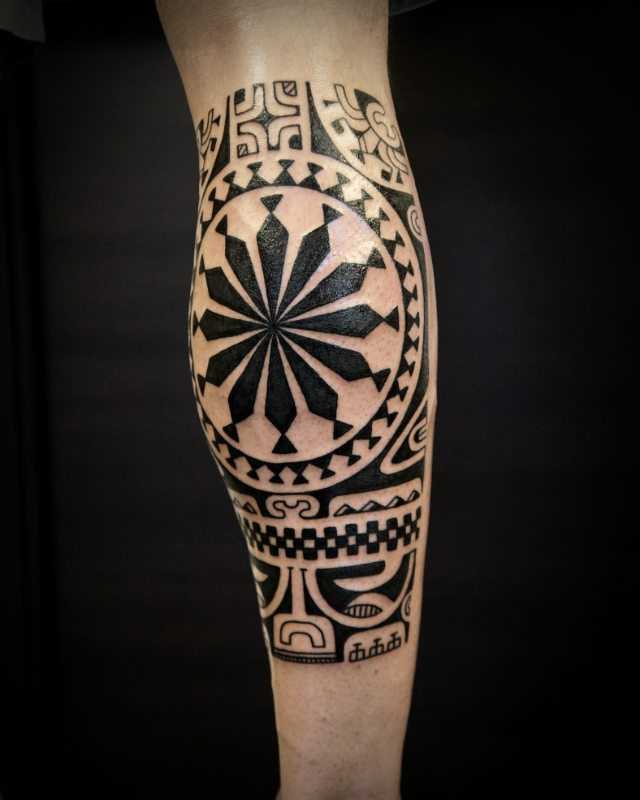Foto da bela tatuagem no estilo polinésia sobre a perna de um cara