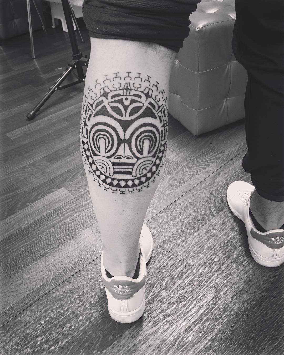 Foto da tatuagem em estilo polinésia sobre a perna de um cara