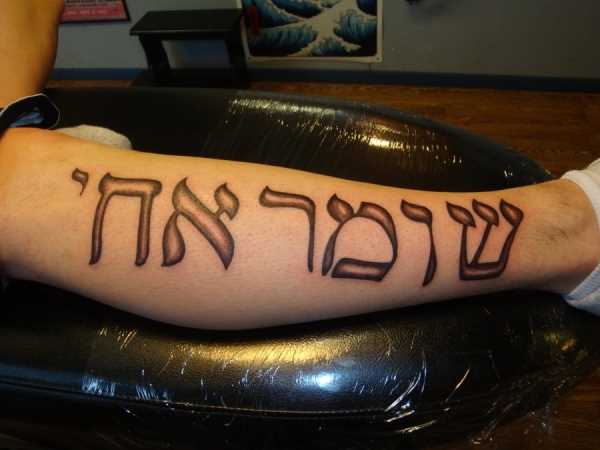 Foto da tatuagem escritos em hebraico em hebraico estilo sobre a perna de um cara