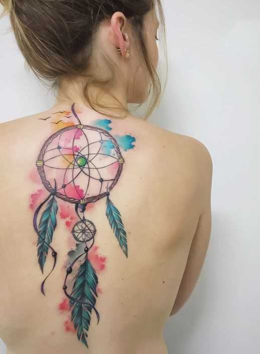 Foto de uma tatuagem de apanhador de sonhos em estilo de aquarela na parte de trás da menina
