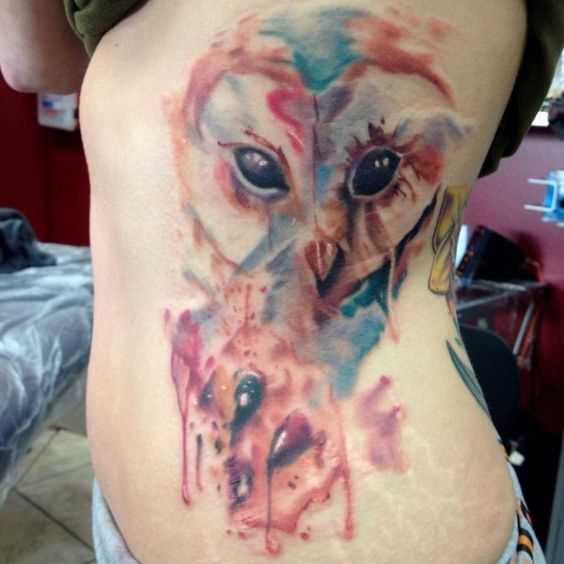 Foto de uma tatuagem de coruja no estilo aquarela lado da menina