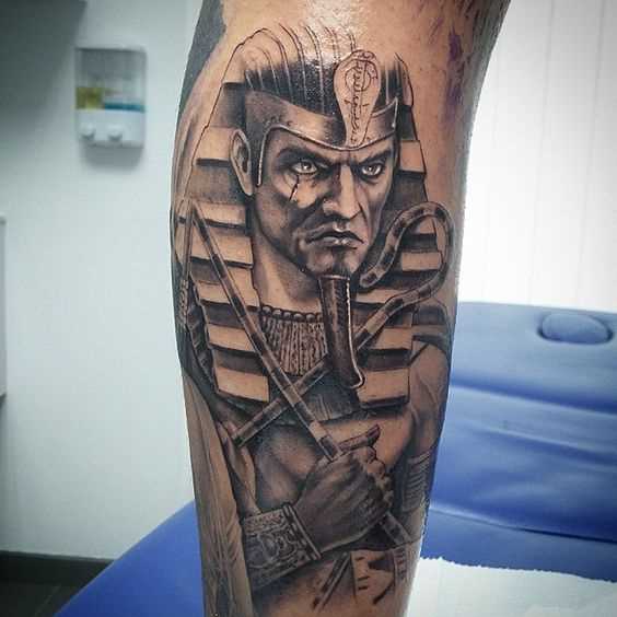 Foto de uma tatuagem de faraó no estilo egípcio sobre a perna de um cara