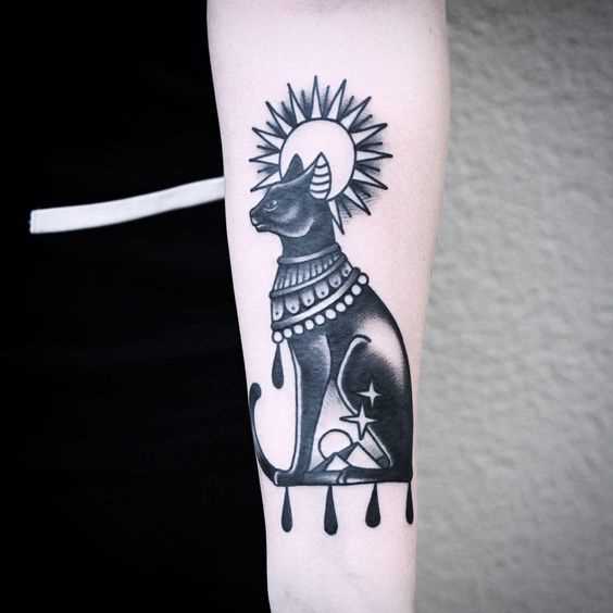 Foto de uma tatuagem de gato em estilo egípcio no antebraço da menina